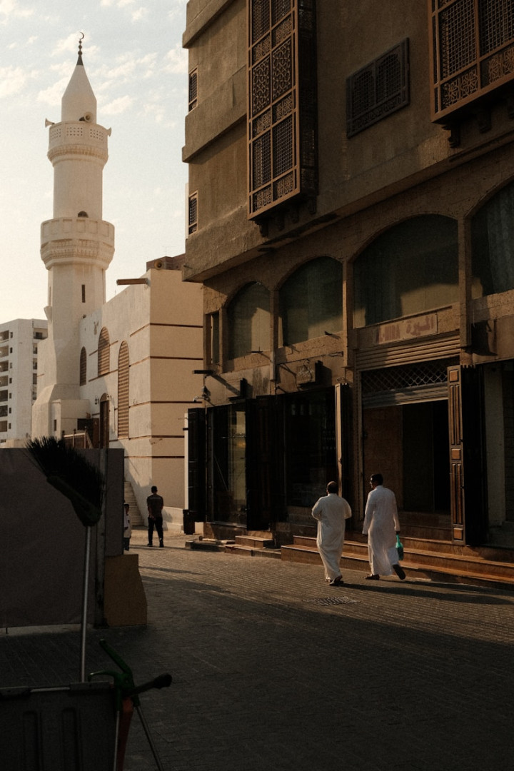 A group of men walking down a street next to tall buildings